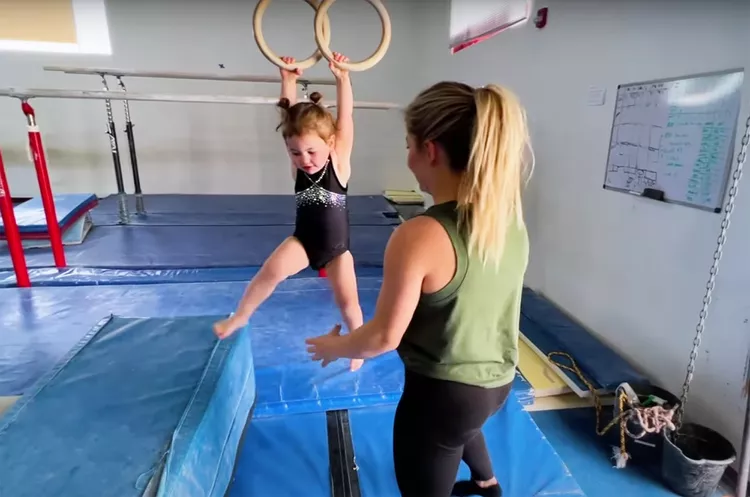 shawn johnson helps child on gymnastics rings